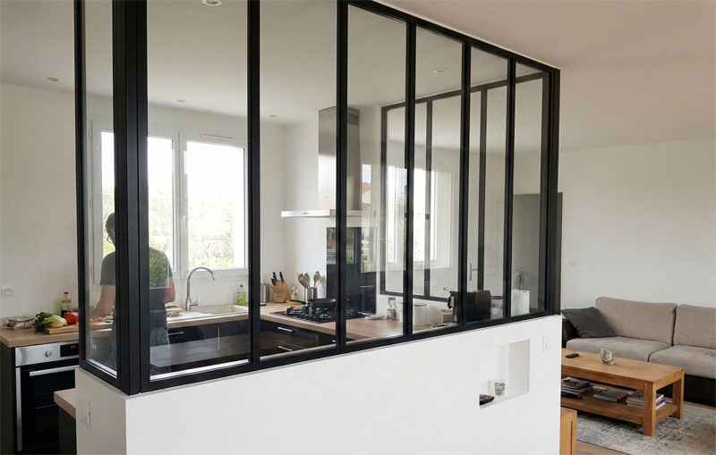 Cuisine moderne avec verrière style atelier noire séparant la pièce de vie et le coin repas.